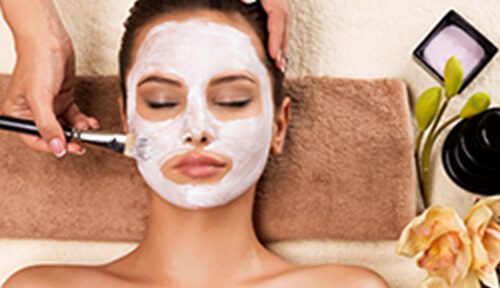 ブラシで顔にパックを塗られている女性