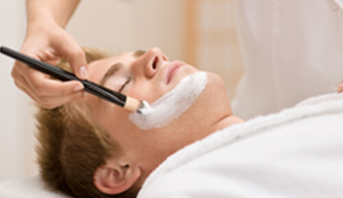 ブラシで顔にパックを塗られている男性