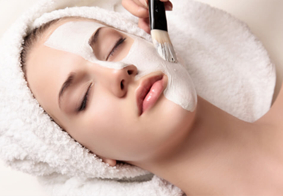 女性の顔にワックスをブラシで塗っている